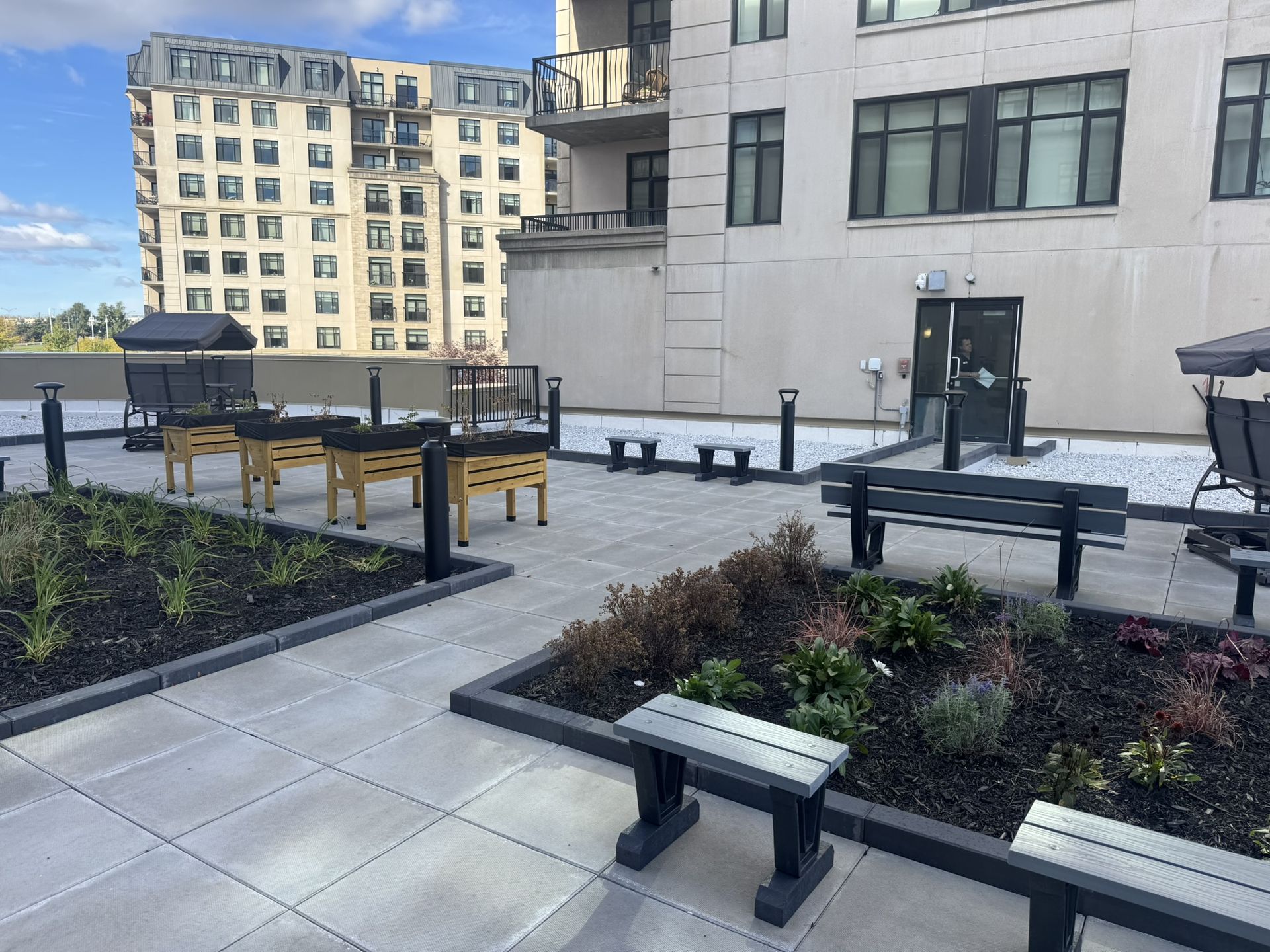 Vegetated roof with planting beds, rest areas, and pavers on a multi-residential building, an example of a green roof developed in Quebec