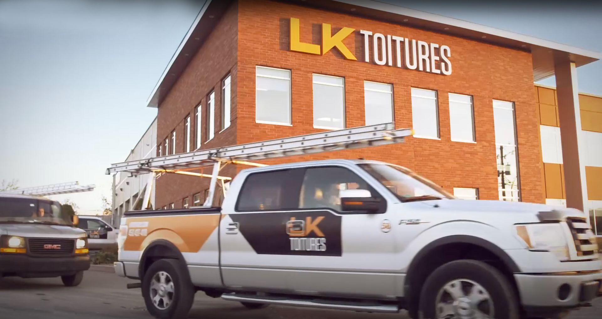 LK Toitures roofing truck in front of a commercial building in Quebec, equipped for roofing work and professional interventions
