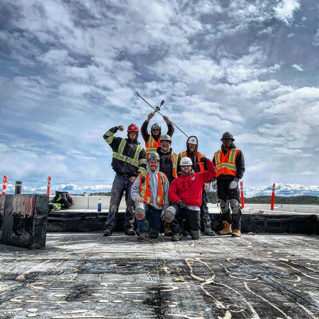 Équipe de couvreurs certifiés travaillant sur un toit plat au Québec avec équipements de sécurité et vêtements haute visibilité