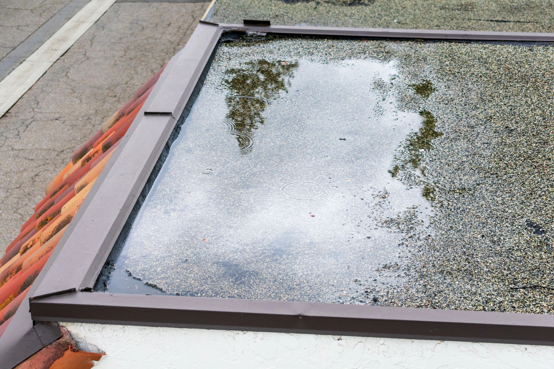  Eau stagnante sur une toiture plate en gravier, près d’un rebord de toit où l’évacuation semble insuffisante